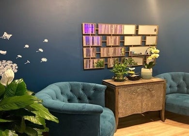 Cozy lounge at Miller Place, New York, US featuring teal armchairs, wall art, and vibrant plants.