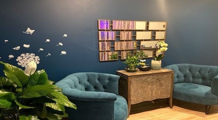Cozy lounge at Miller Place, New York, US featuring teal armchairs, wall art, and vibrant plants.