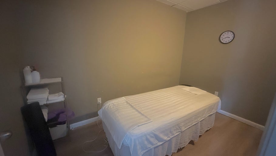 Tranquil massage room at East Setauket in Setauket- East Setauket, New York, US, with a neatly made bed.