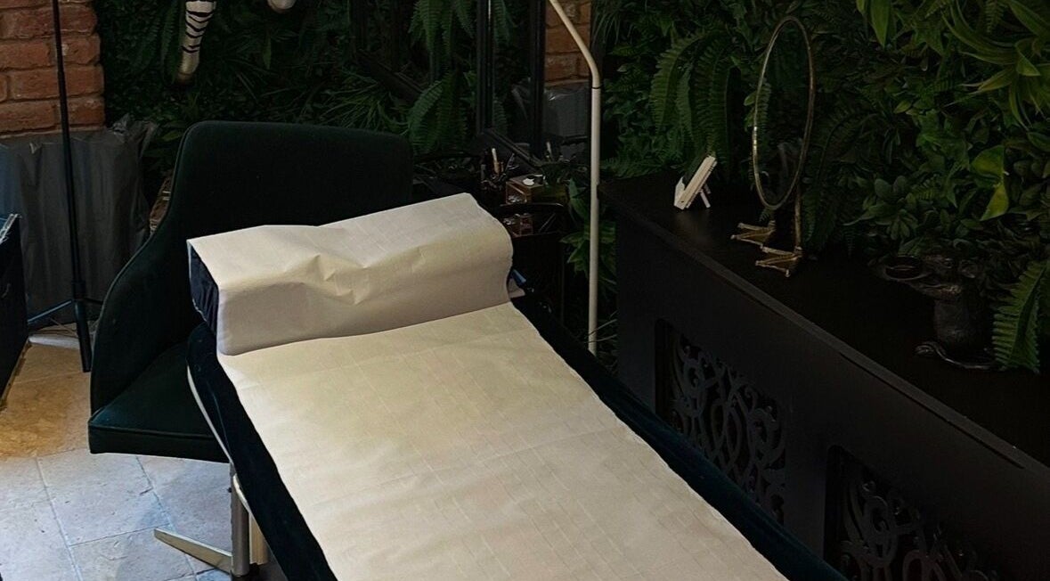 Serene treatment room at I D BEAUTY, Stoke-on-Trent, England, GB, featuring a lush green decor and comfortable massage table.