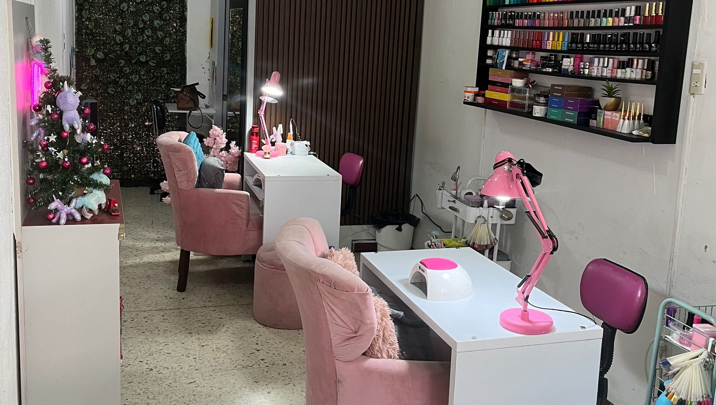 Interior de Páramo Nails Qro en Santiago De Querétaro con sillas rosas y productos de uñas en estantería.