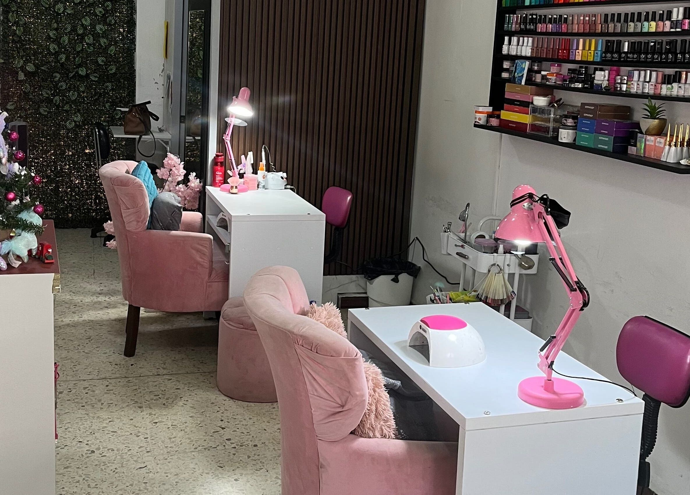 Interior de Páramo Nails Qro en Santiago De Querétaro con sillas rosas y productos de uñas en estantería.
