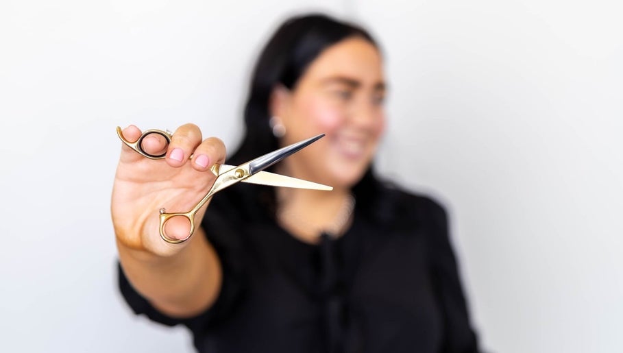 Stylist holding shears at The Hair Lounge in Emerald, Queensland, AU, offering expert haircut services.