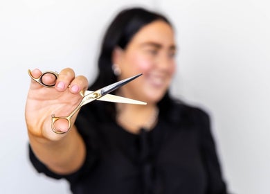 Stylist holding shears at The Hair Lounge in Emerald, Queensland, AU, offering expert haircut services.