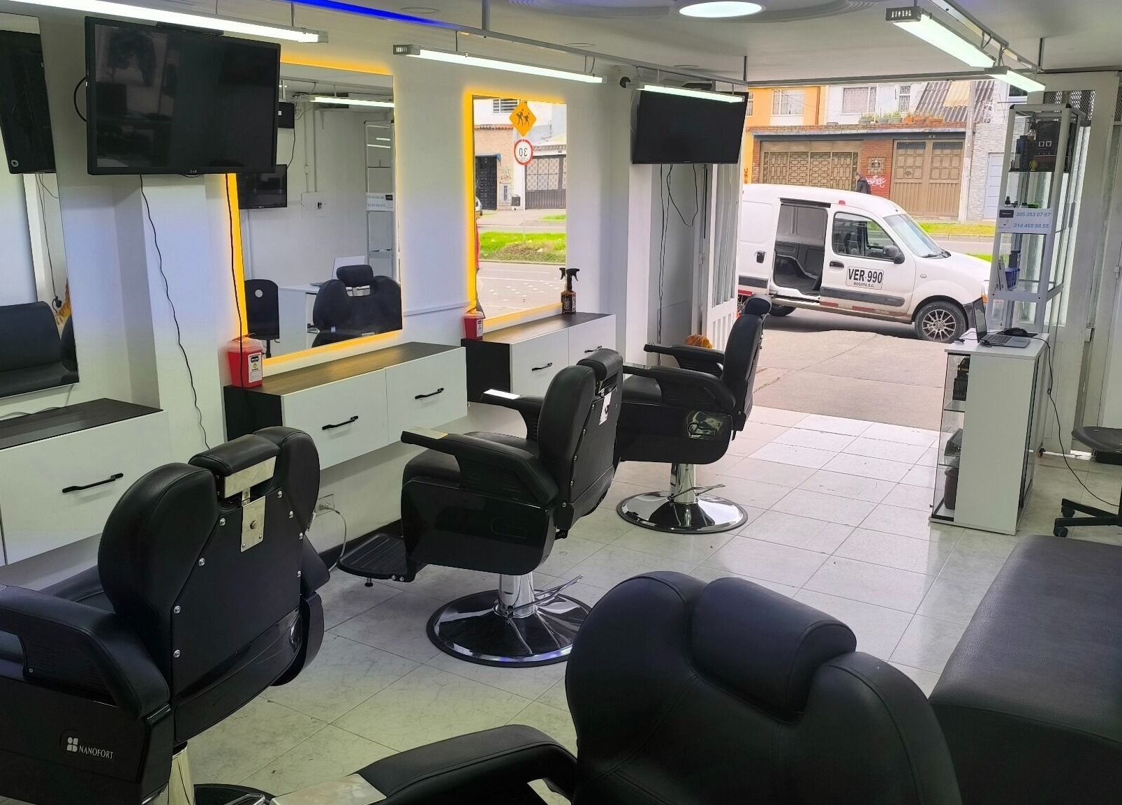 Interior moderno de Barbería LUXFADE en Bogotá, Bogotá, CO, mostrando sillas de barbería elegantes y espejos iluminados.