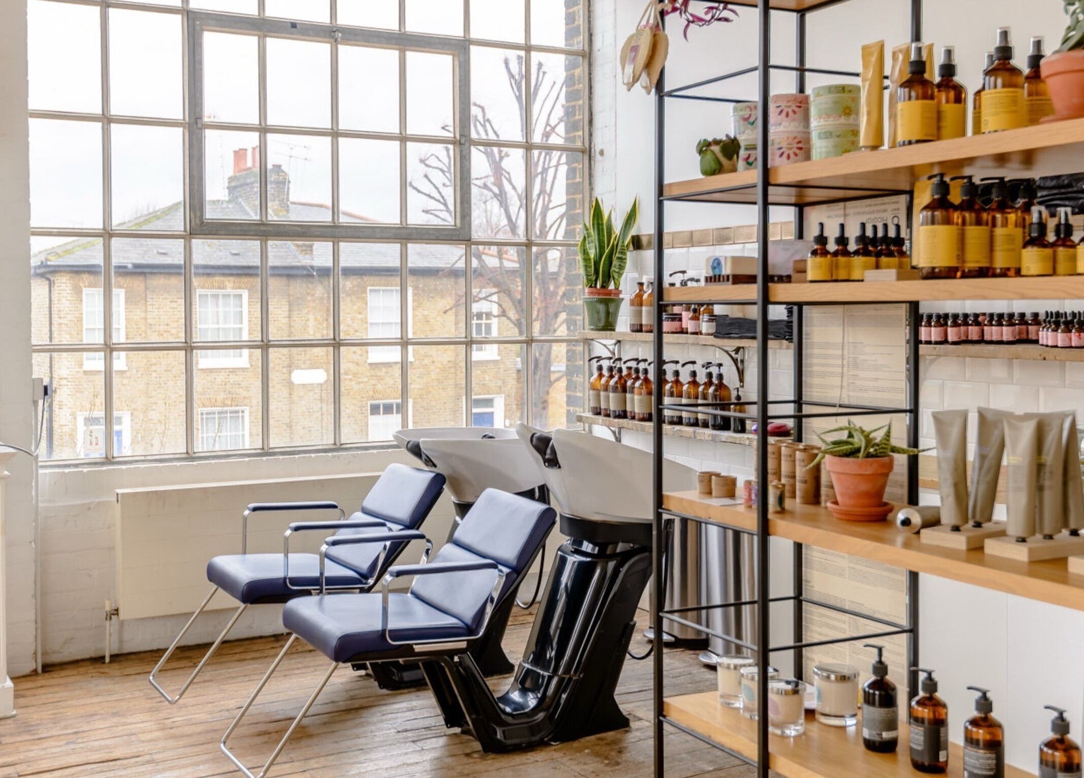 Bright, stylish interior of Ricky Alexander Hair in London, GB with modern seating and products on display.