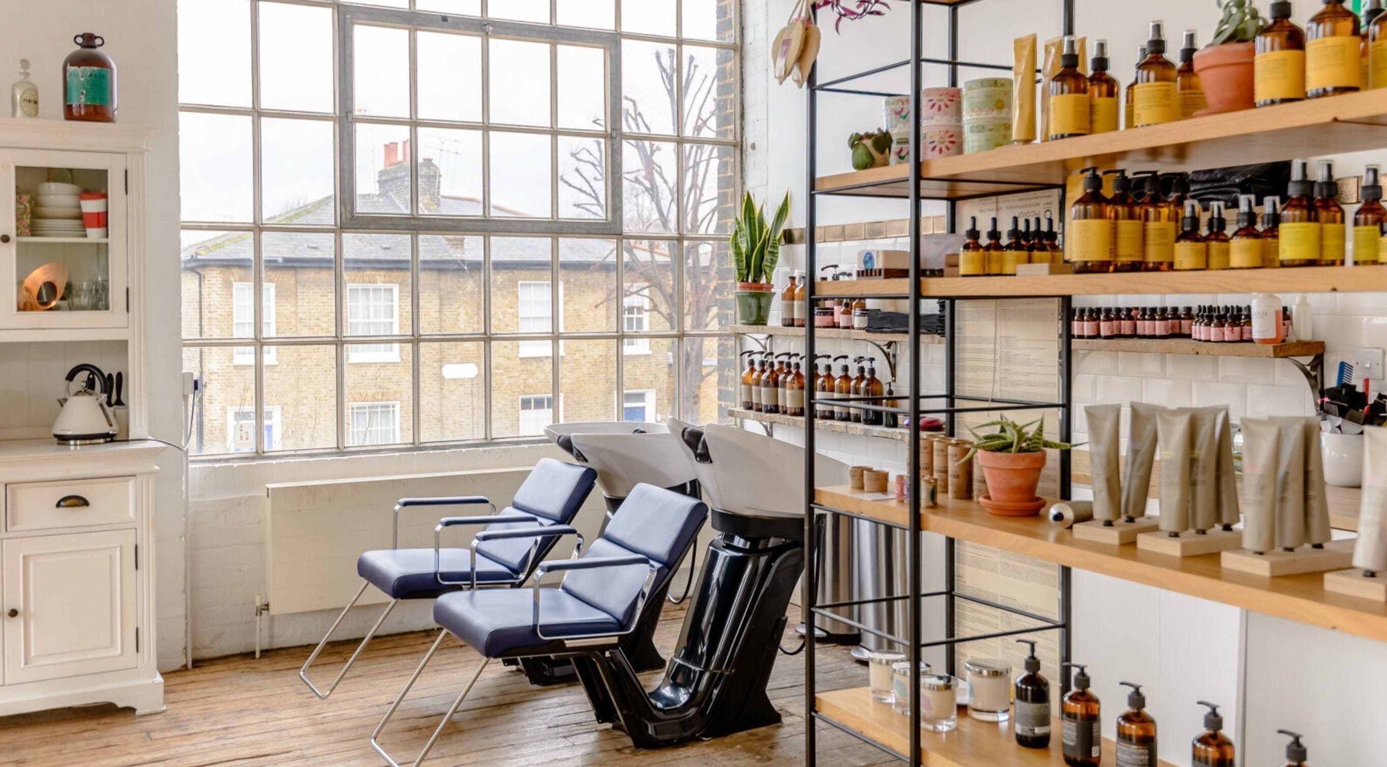 Bright, stylish interior of Ricky Alexander Hair in London, GB with modern seating and products on display.