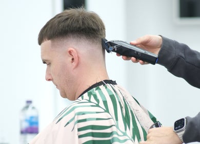 A stylist at Source Barbers in Aberdeen, Scotland, GB, expertly trims a man's hair with clippers.