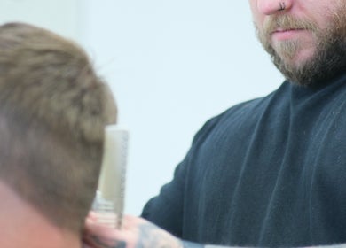 Barber at Source Barbers in Aberdeen, Scotland, GB skillfully cutting a client's hair.