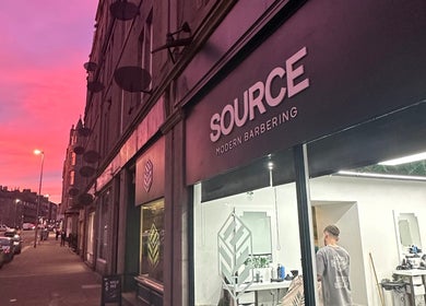 Source Barbers in Aberdeen, Scotland, GB at sunset with a vibrant pink sky and street view.