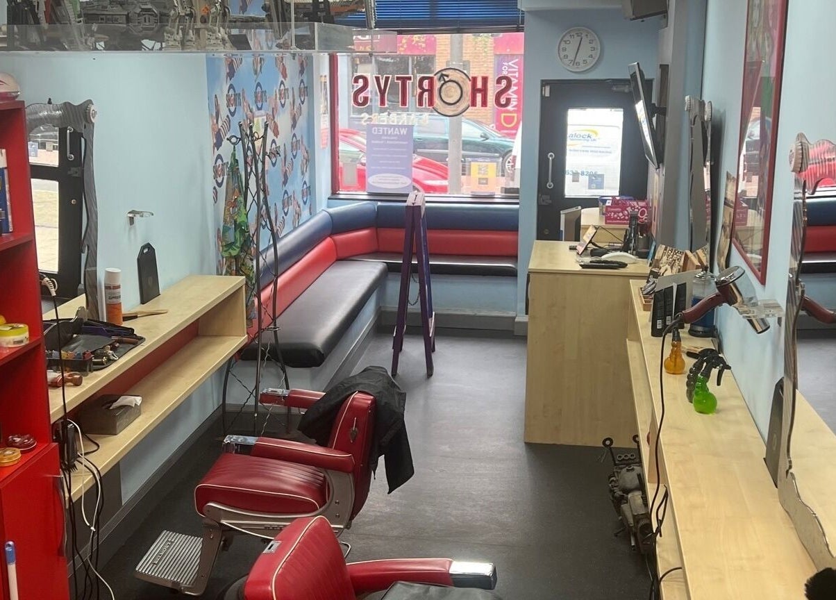 Interior of Shortys - Hinckley, a vibrant salon in Hinckley, England, GB with red chairs and modern decor.