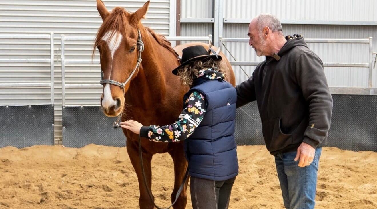 Trainer guiding a person with a horse at Scott Brodie - Central Coast, Peats Ridge, New South Wales, AU.