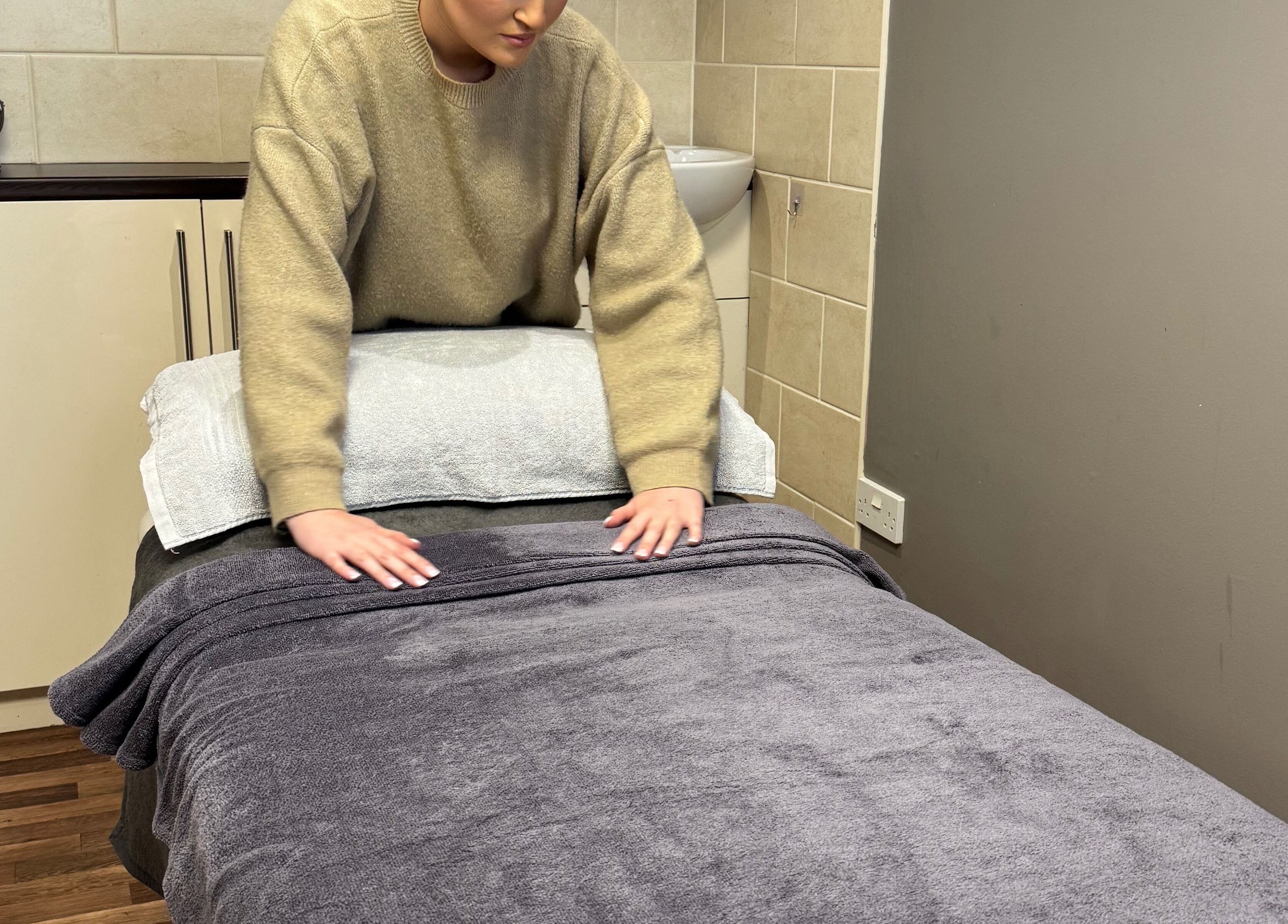 Therapist preparing a massage table at BeautyByEve, Sidmouth, England, GB for a relaxing spa session.
