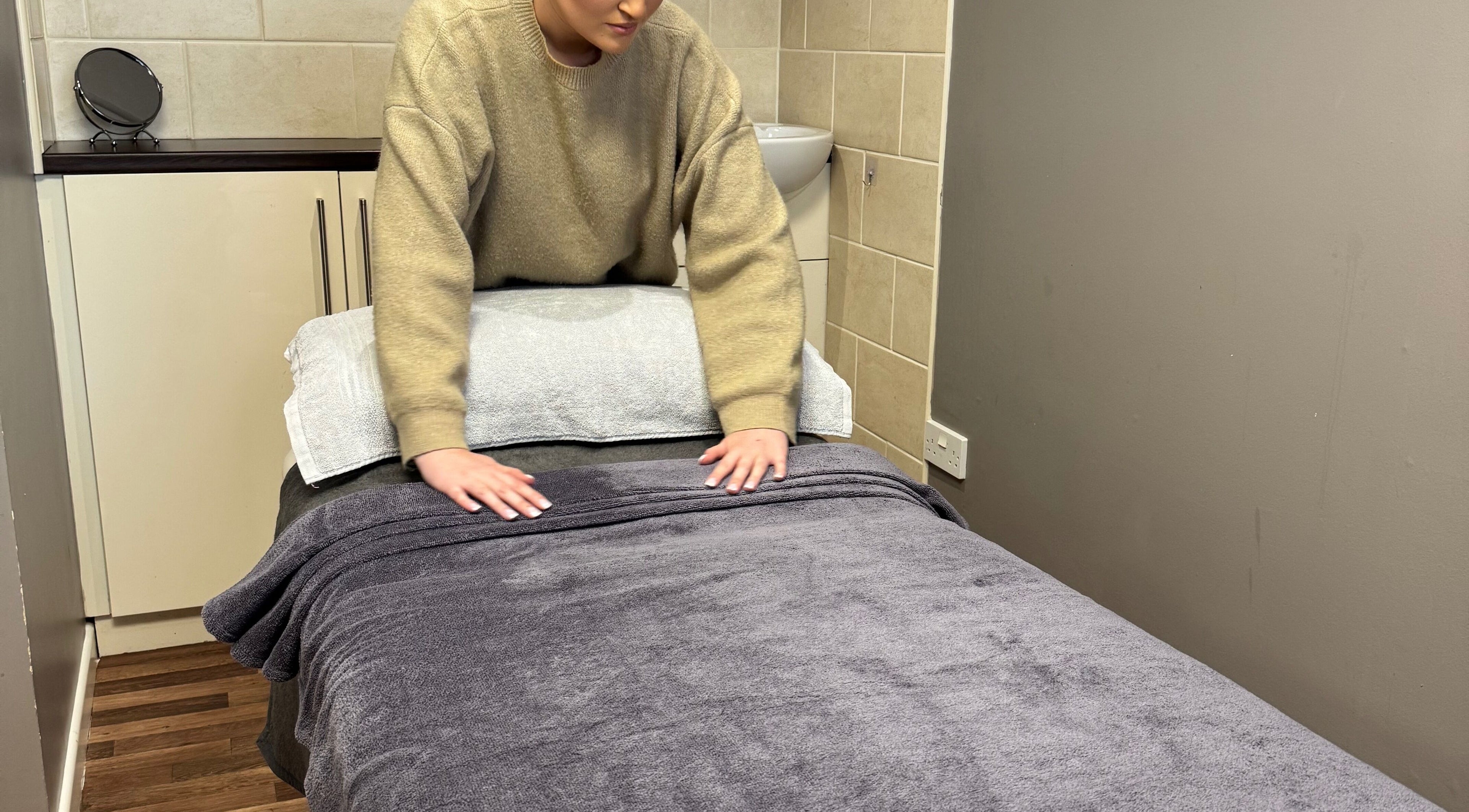 Therapist preparing a massage table at BeautyByEve, Sidmouth, England, GB for a relaxing spa session.