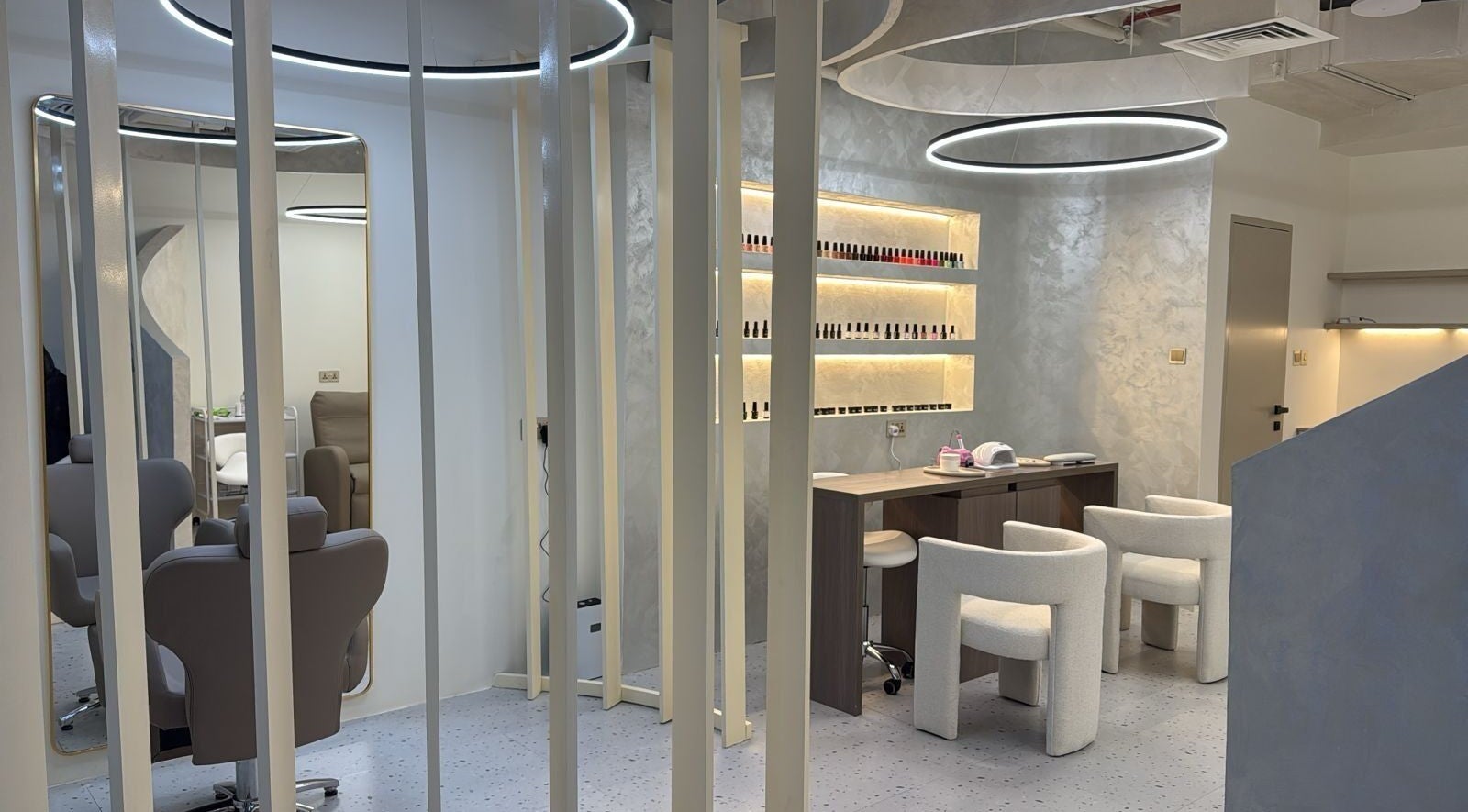Modern interior of Lash Lab Beauty Salon L.L.C in Dubai, AE featuring stylish chairs and nail polish display.