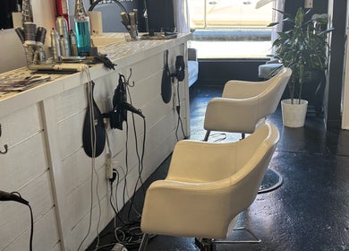 ASHIYA'S salon chairs and styling station in Jersey City, New Jersey, US, featuring white chairs and beauty tools.