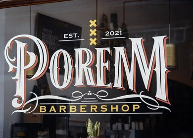 Elegant sign of Porem Damsquare barbershop in Amsterdam, Noord-Holland, NL, featuring classic typography.