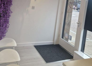 Inviting entryway at Skin By Shannon, Tranent, Scotland, GB with white chairs and purple flower decor.