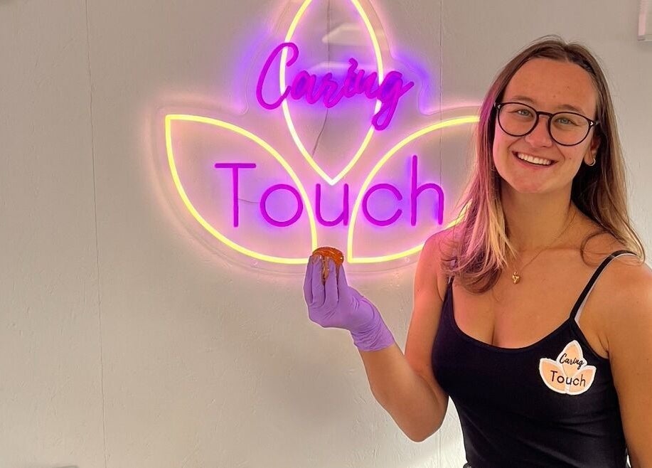 Persoon bij het verlichte Caring Touch-logo in Tessenderlo-Ham, Vlaanderen, BE.