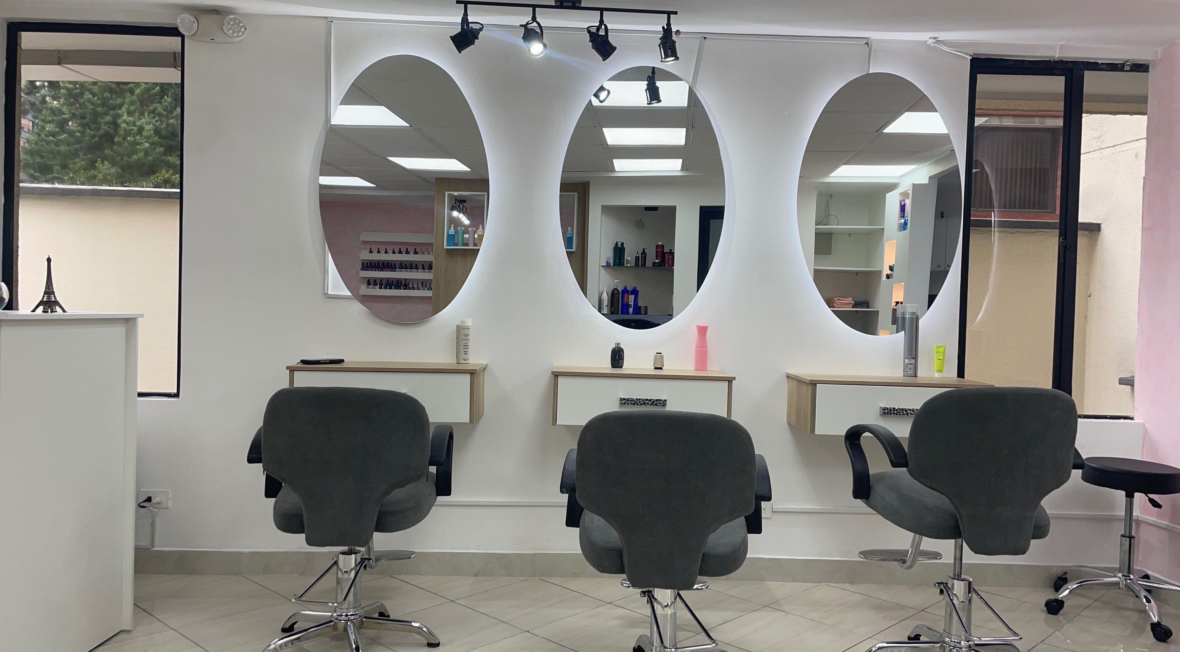 Interior moderno de Warmi Beauty Studio en Quito, Pichincha, EC con espejos ovalados y sillas de estilista.