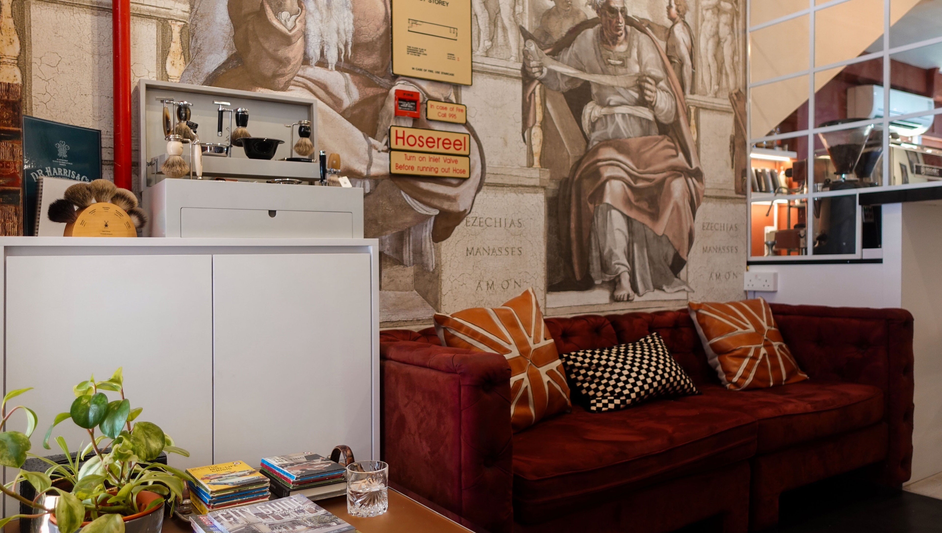 Chic lounge area with red sofa at Jermyn Street, Singapore, SG, adorned by artistic wall mural.