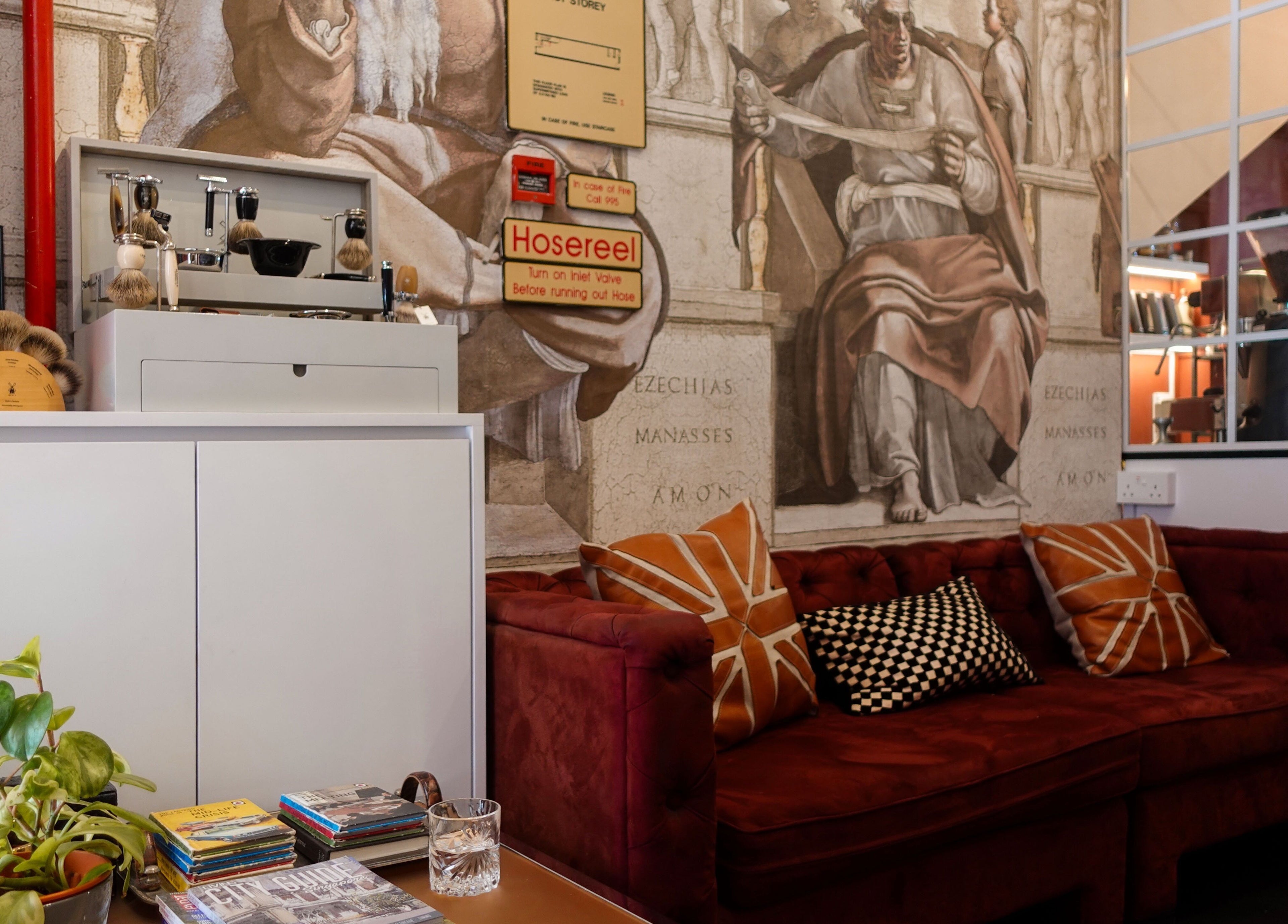 Chic lounge area with red sofa at Jermyn Street, Singapore, SG, adorned by artistic wall mural.