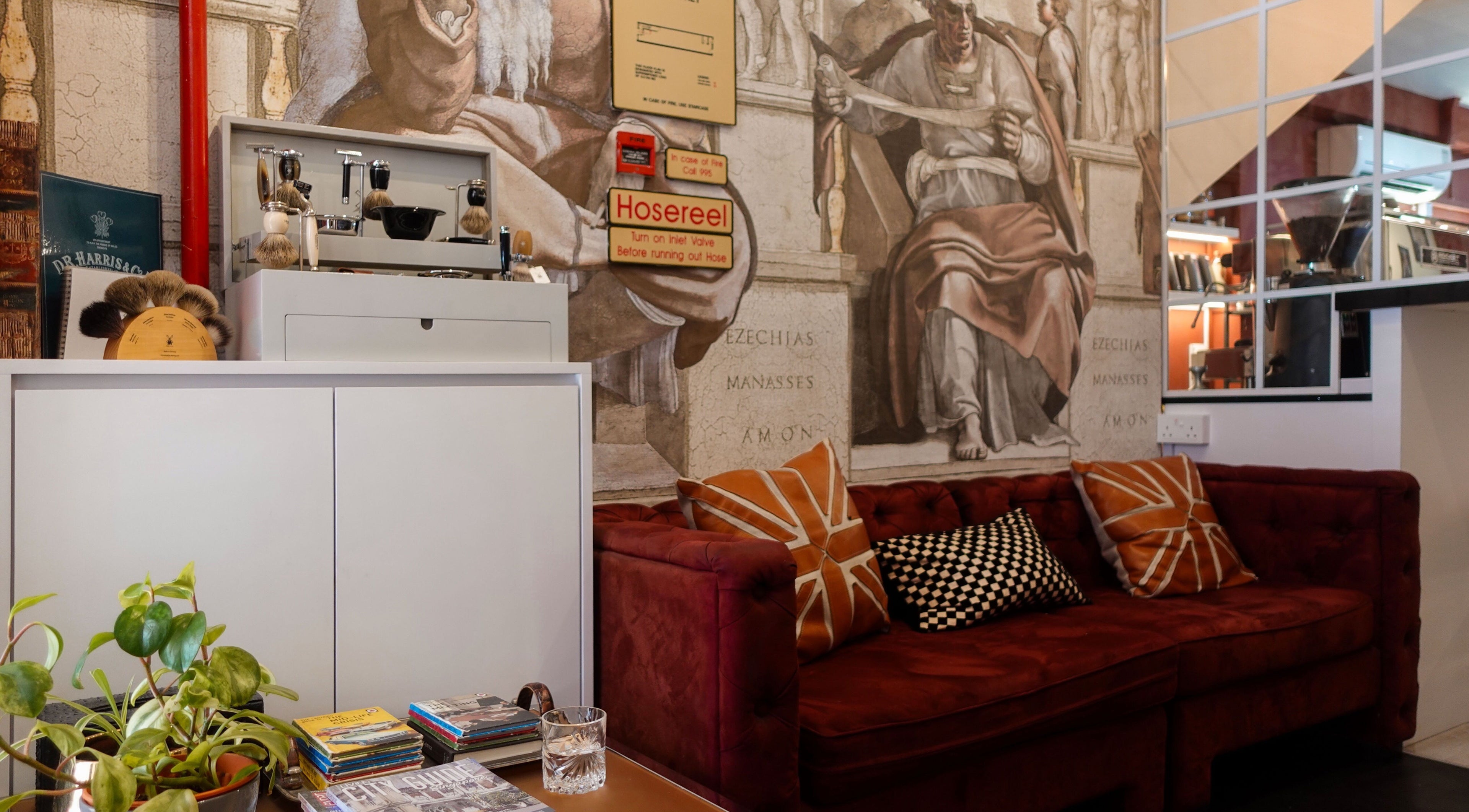 Chic lounge area with red sofa at Jermyn Street, Singapore, SG, adorned by artistic wall mural.