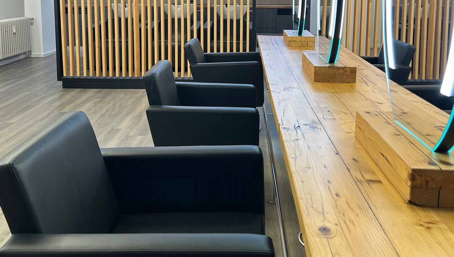 Moderne Einrichtung bei LucaHair, Düsseldorf, Nordrhein-westfalen, DE. Schwarze Sessel an Holztisch mit Spiegeln.
