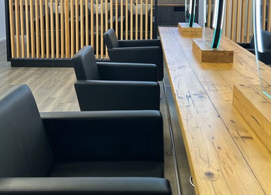 Moderne Einrichtung bei LucaHair, Düsseldorf, Nordrhein-westfalen, DE. Schwarze Sessel an Holztisch mit Spiegeln.