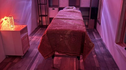 Cozy treatment room at Amethyst Touch, Poole, England, GB with ambient lighting and massage table.
