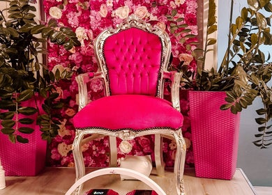Eleganter pinker Sessel bei Pink Flamingo Beauty, Neuenegg, Bern, CH, umgeben von grünen Pflanzen.