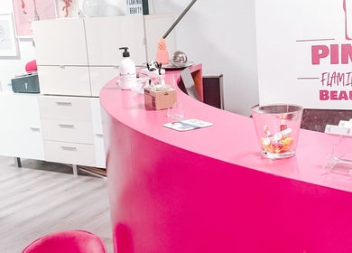 Empfangsbereich bei Pink Flamingo Beauty, Neuenegg, Bern, CH, mit rosa Theke und Dekoration.