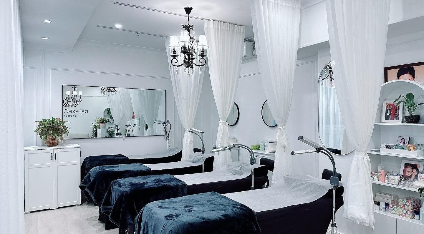 Chic interior of DE LASH MOSMAN in Mosman, New South Wales, AU with elegant spa beds and white curtains.