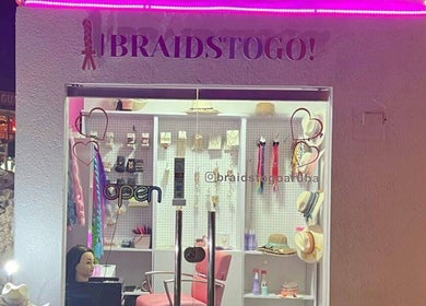 Braids To Go venue in Noord, AW showcasing stylish braiding supplies and fashionable hats.