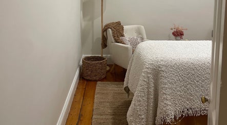 Warm, inviting treatment room at Rose Rituals in Melbourne, Victoria, AU, featuring a plush chair and soft blankets.