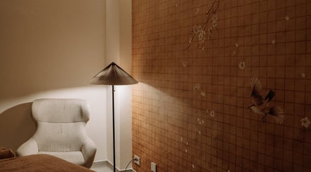 Cameră relaxantă la Hanami Spa, București, cu scaun confortabil și decor floral pe perete.
