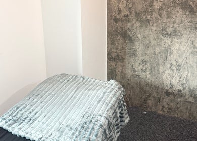 Relaxing treatment area at The Blink Atelier LDN, London, England, GB, with plush grey blanket and textured wall.