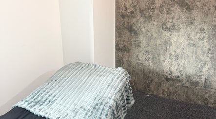 Relaxing treatment area at The Blink Atelier LDN, London, England, GB, with plush grey blanket and textured wall.