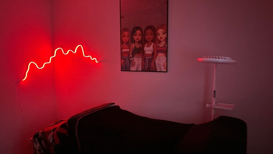 Cozy treatment room at Bratzified Beauty in Douglas, Arizona, US with red neon light and stylish decor.
