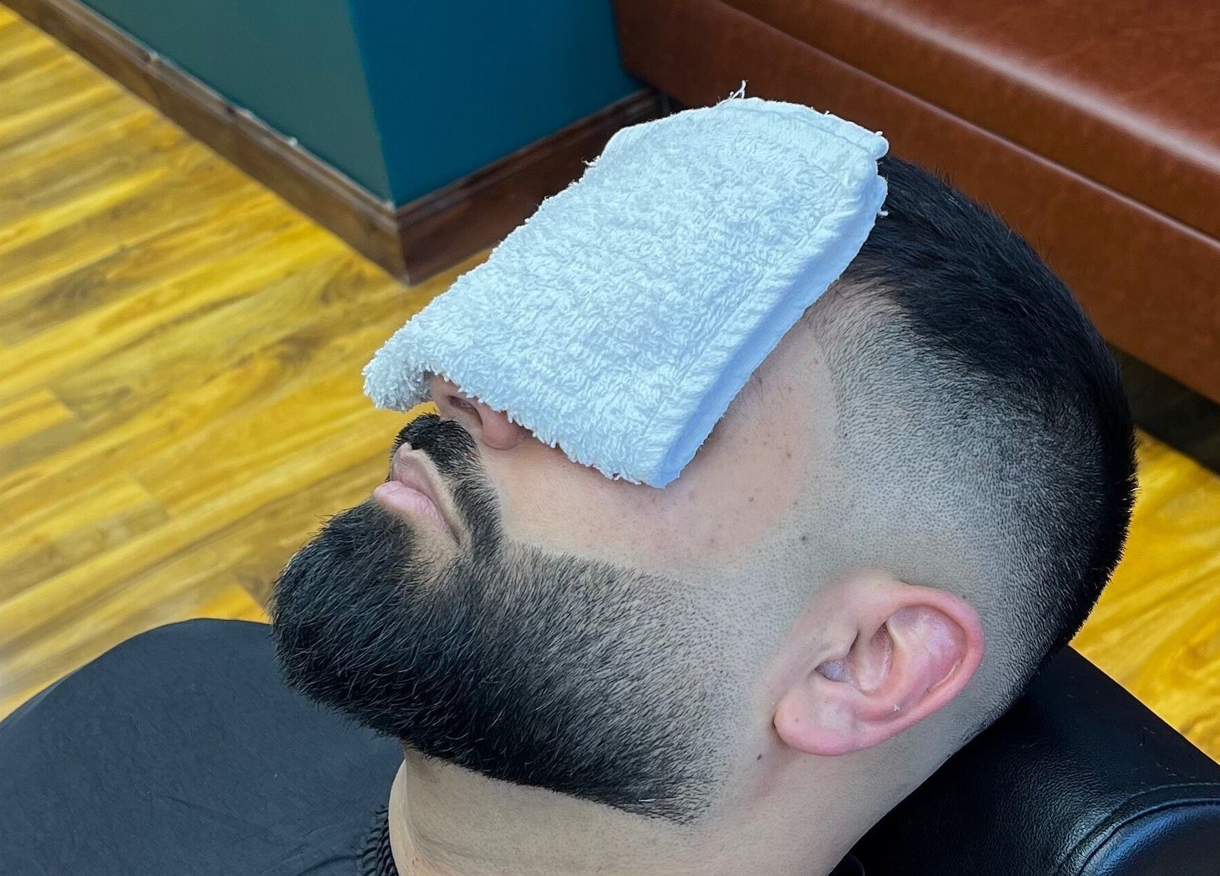 Man enjoying a grooming session at Fade Factory - Balham, London, England, GB with a towel on his face.