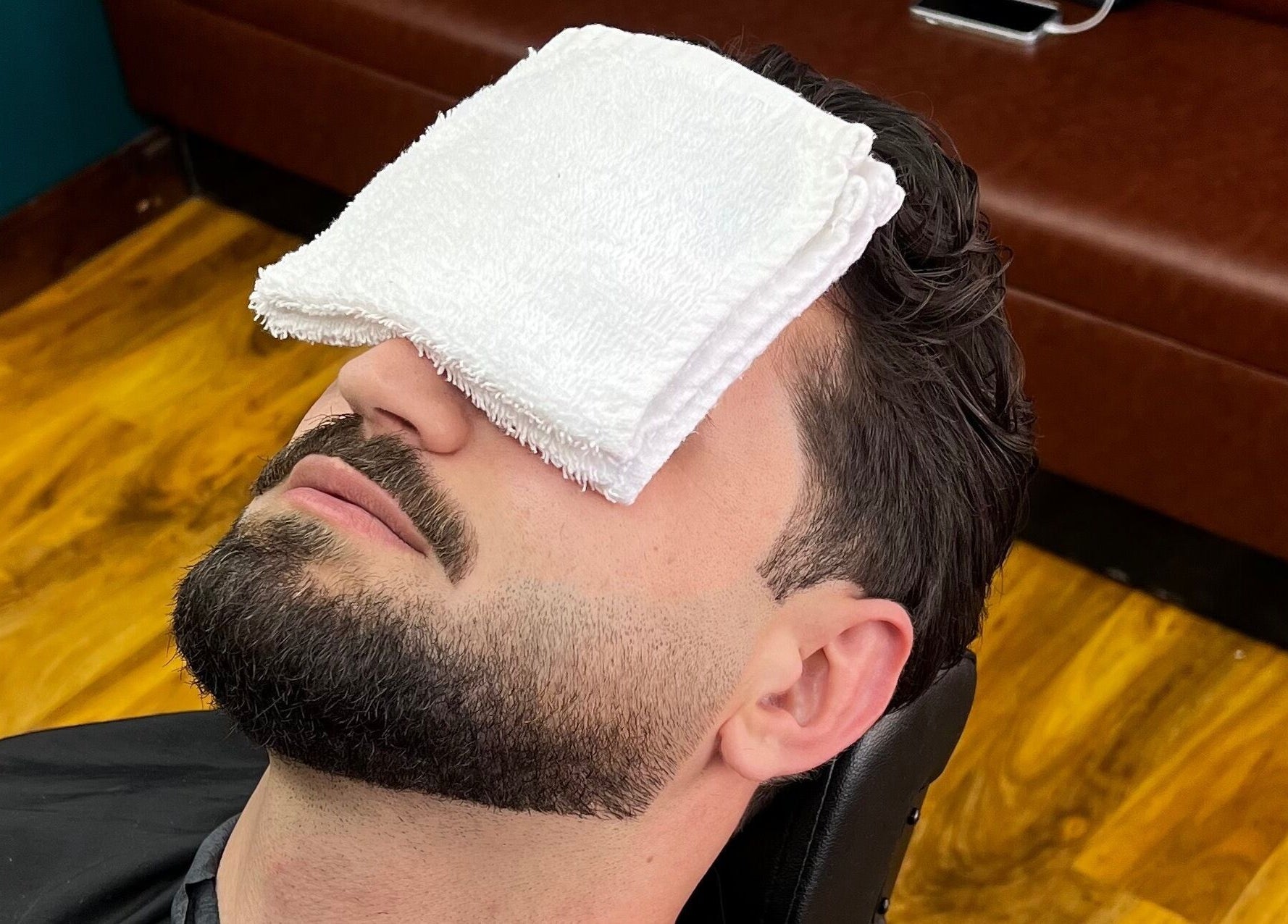 Man enjoying facial towel treatment at Fade Factory, Morden, England, GB.