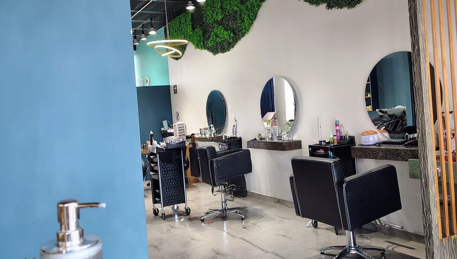 Salón moderno de belleza en Glow - Zibata, Zibatá, Querétaro, MX con decoración verde y asientos negros.