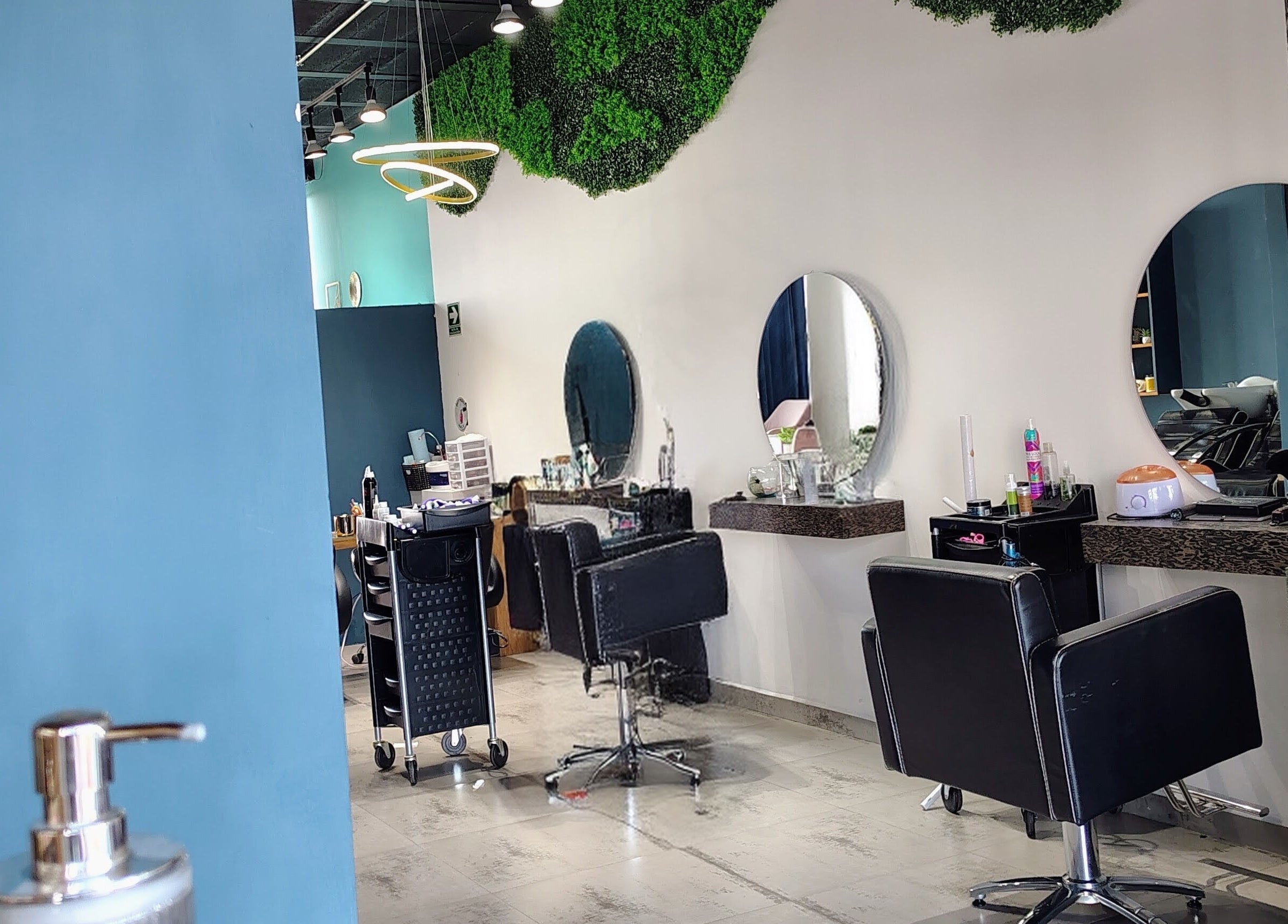 Salón moderno de belleza en Glow - Zibata, Zibatá, Querétaro, MX con decoración verde y asientos negros.
