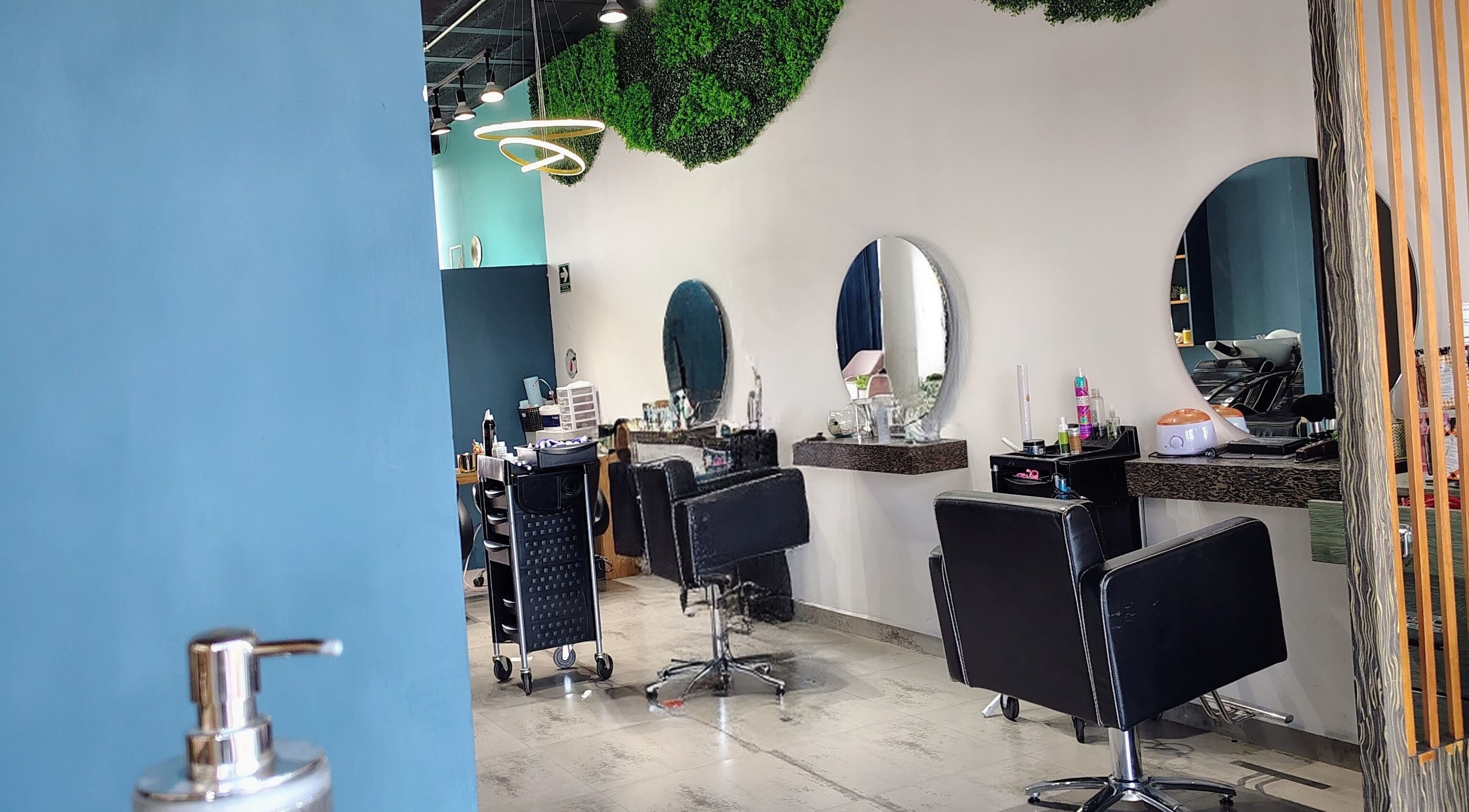 Salón moderno de belleza en Glow - Zibata, Zibatá, Querétaro, MX con decoración verde y asientos negros.