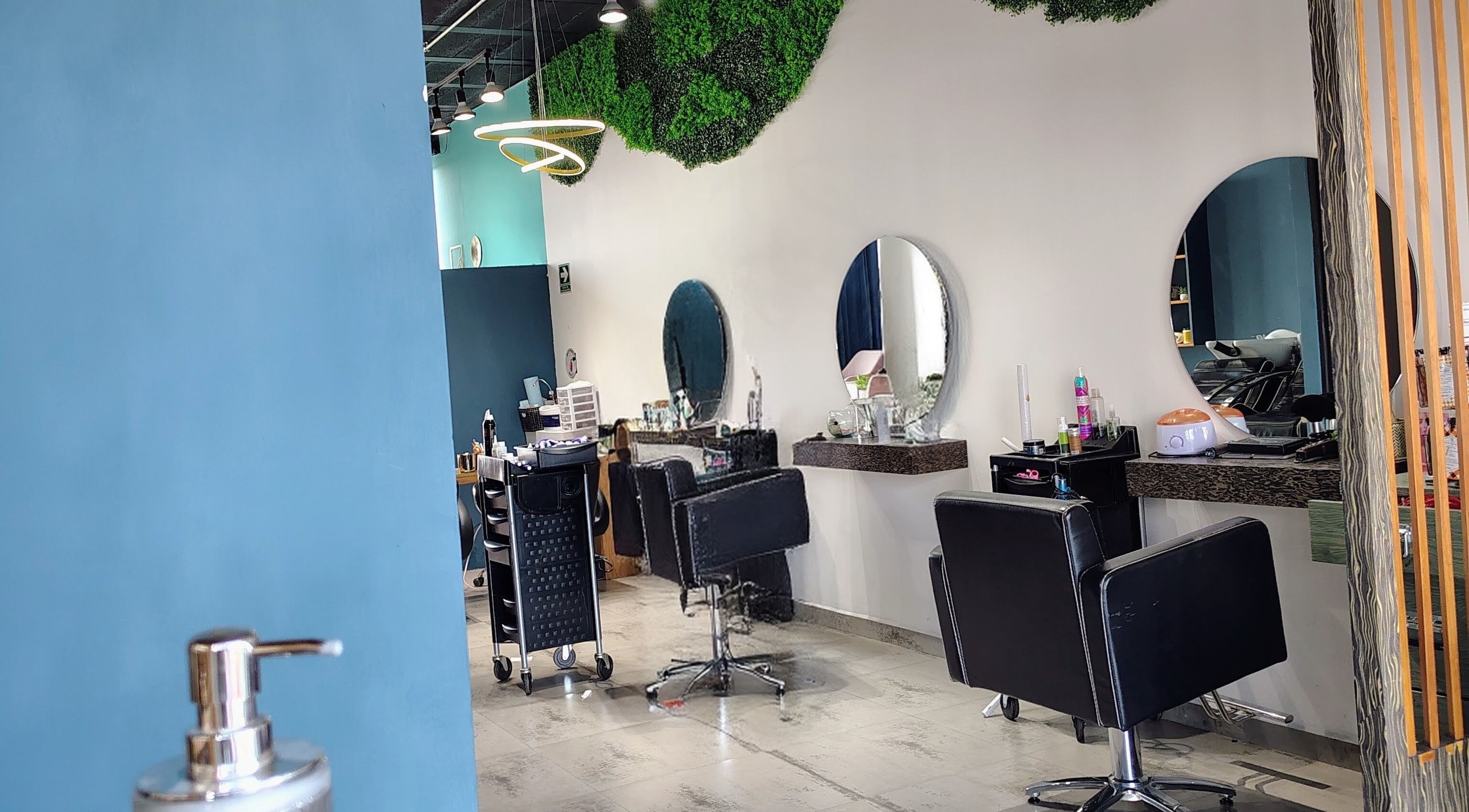 Salón moderno de belleza en Glow - Zibata, Zibatá, Querétaro, MX con decoración verde y asientos negros.