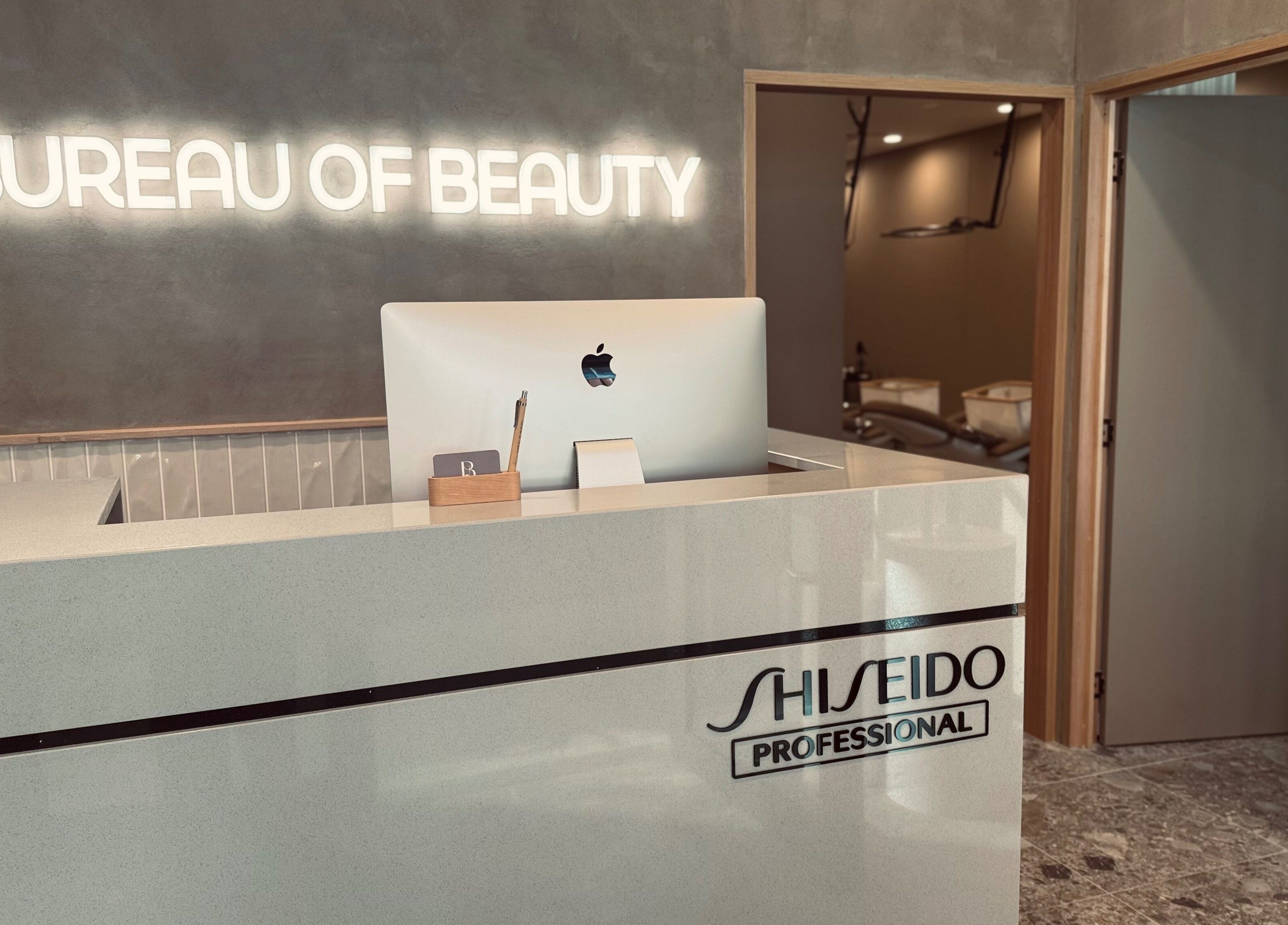 Reception desk at Bureau of Beauty, Yeerongpilly, Queensland, AU, featuring a sleek design and glowing signage.