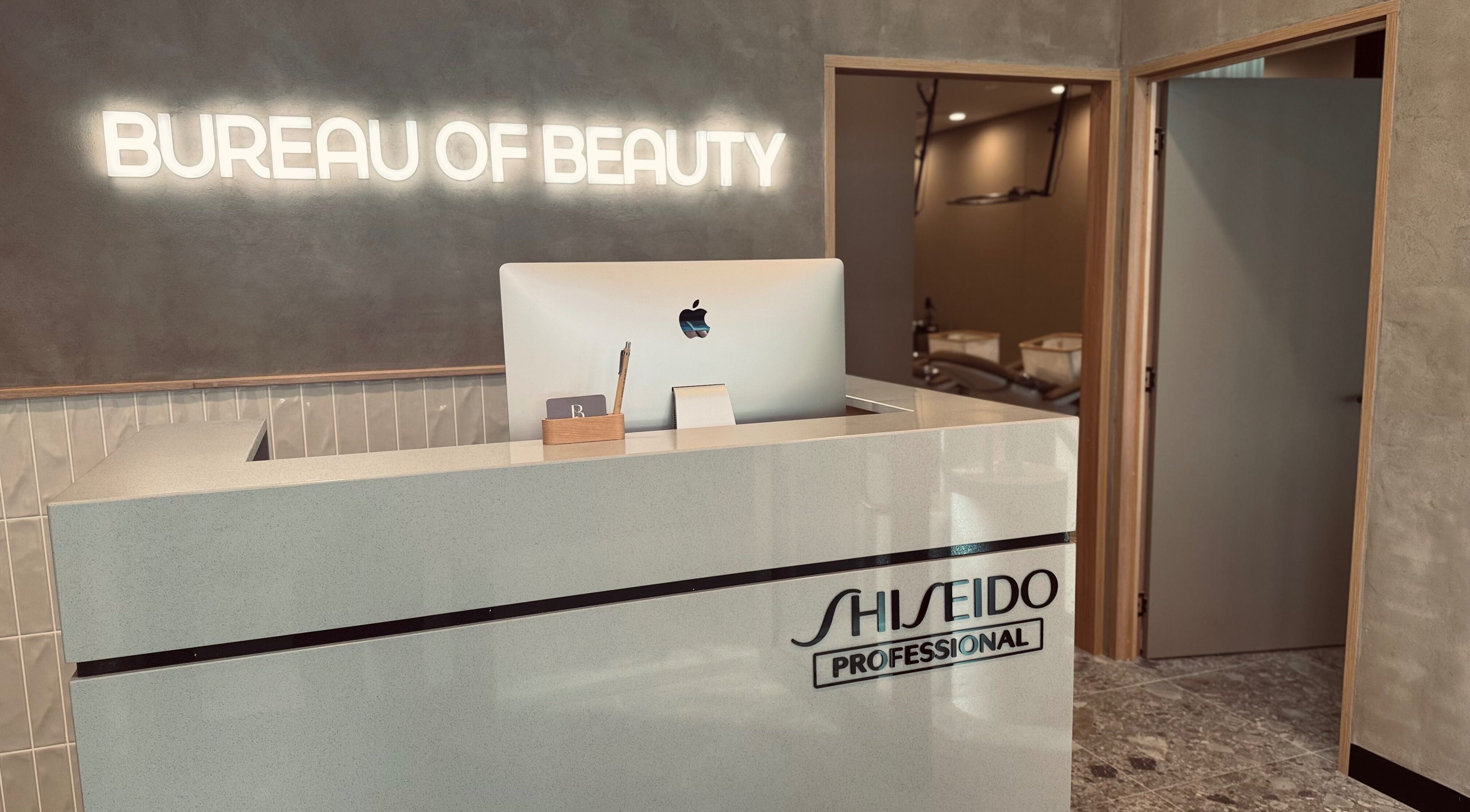 Reception desk at Bureau of Beauty, Yeerongpilly, Queensland, AU, featuring a sleek design and glowing signage.