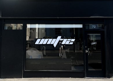 Exterior of Unit 72 Barbershop at 72, Cheltenham, England, GB showcasing modern black signage.