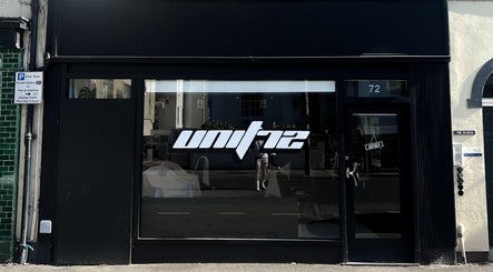Exterior of Unit 72 Barbershop at 72, Cheltenham, England, GB showcasing modern black signage.