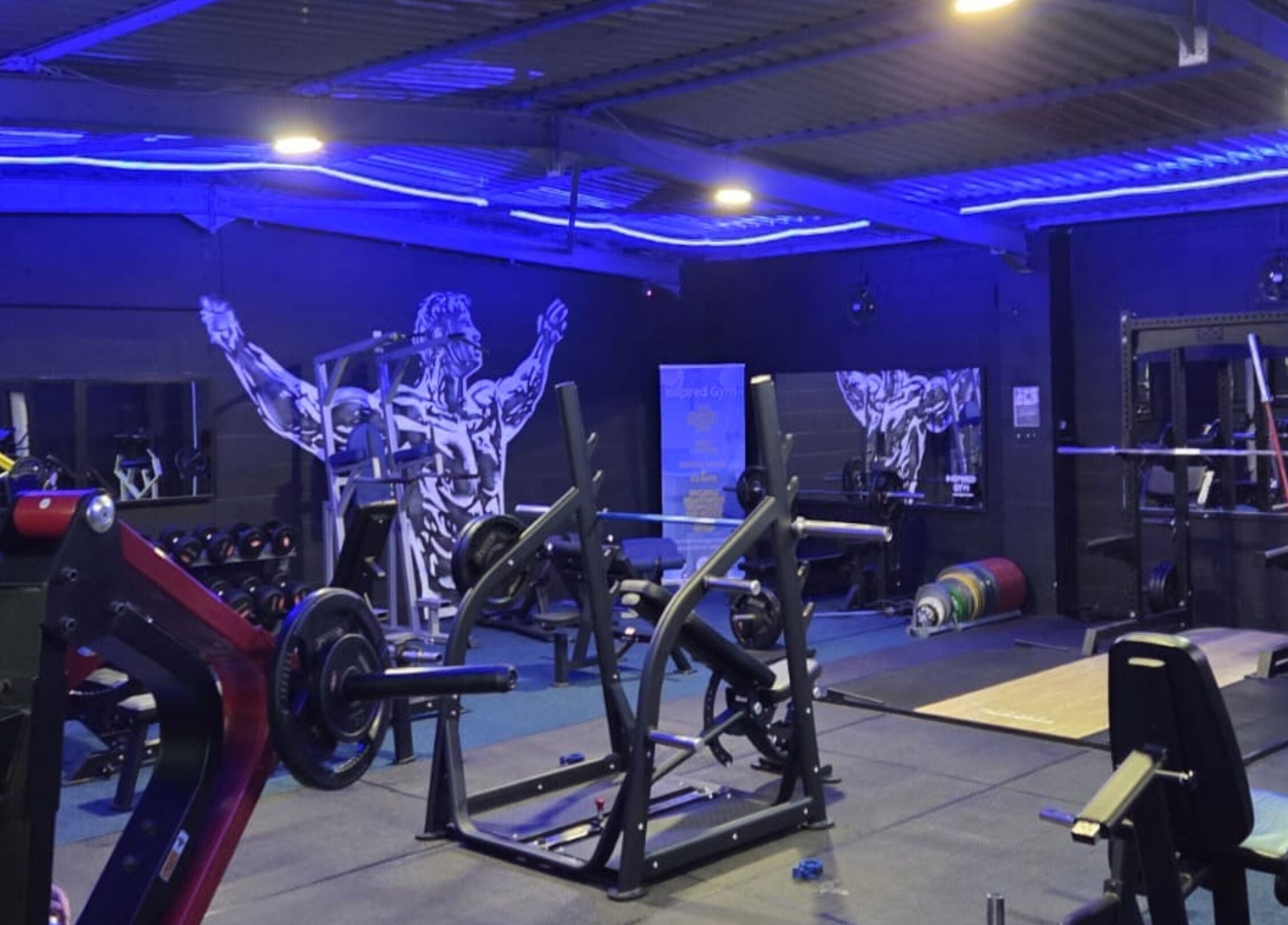 Modern gym interior at 360 Healthcare Hub, Wigan, England, GB with weightlifting equipment and bold wall art.